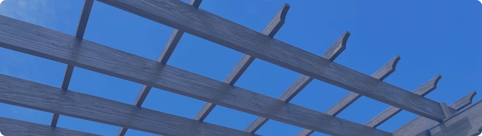 Wooden pergola structure against a clear blue sky, showcasing deck painting and staining services by Trusted Painters LLC.